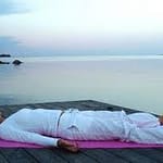 donna a terra su spiaggia yoga nidra